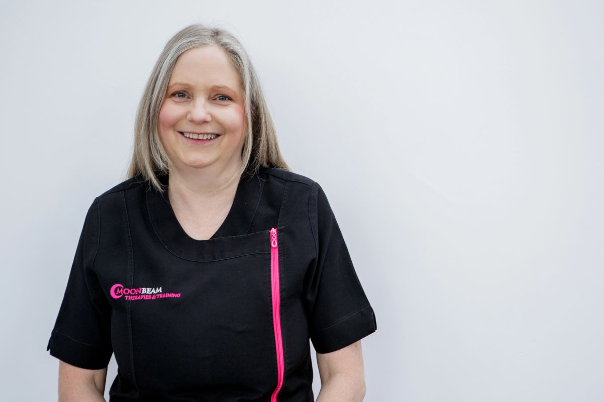 Karen Hooton standing in her first aid training uniform - black with pink writing for the logo Moonbeam Therapies & Training